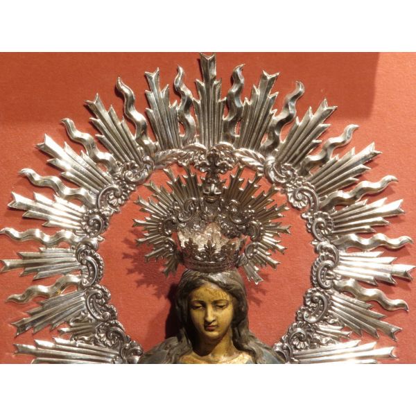 Virgen en escayola policromada con corona y aureola de plata sobre fondo de terciopelo