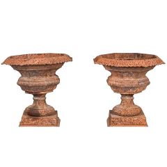 Un par de urnas de hierro fundido estilo francés de pátina roja. 